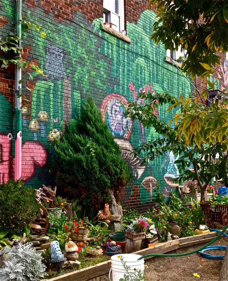 Fairyland Mural painted on a brick wall with willow trees framing a unicorn, fairies, mushrooms, an owl and flowers