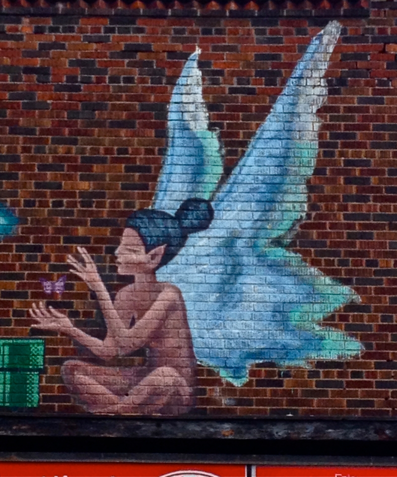 Blue-Winged Fairy playing with purple butterfly painted on brick wall