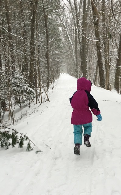 child skipping along wooded path